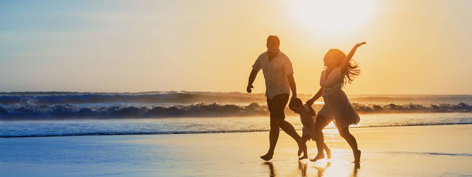 Family having fun on the beach at sunset.