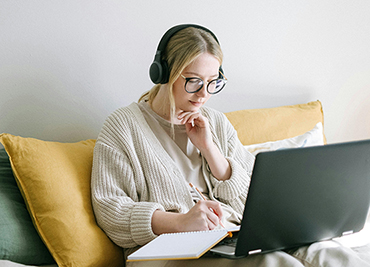 woman with headphones on looking at laptop